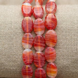 beads with red and white striped beads on a textured beige fabric background